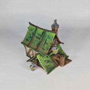 May include: A miniature wooden house with a green tiled roof and a chimney. The house has two windows and a door, and there are lanterns hanging from the eaves.