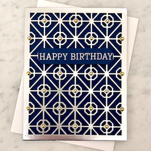 May include: A navy blue card with a silver geometric pattern and gold accents. The card says "Happy Birthday" in white lettering.