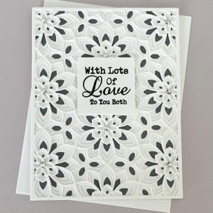 May include: White greeting card with a floral design and the words "With Lots of Love To You Both". The card has a layered, textured appearance with small crystal embellishments. A white envelope is visible.