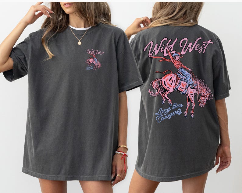 May include: Dark gray t-shirt with a graphic on the front and back. The front graphic says "Wild West" with a small image of a cowgirl riding a horse. The back graphic says "Wild West" with a cowgirl riding a horse and the words "Long live Cowgirls."