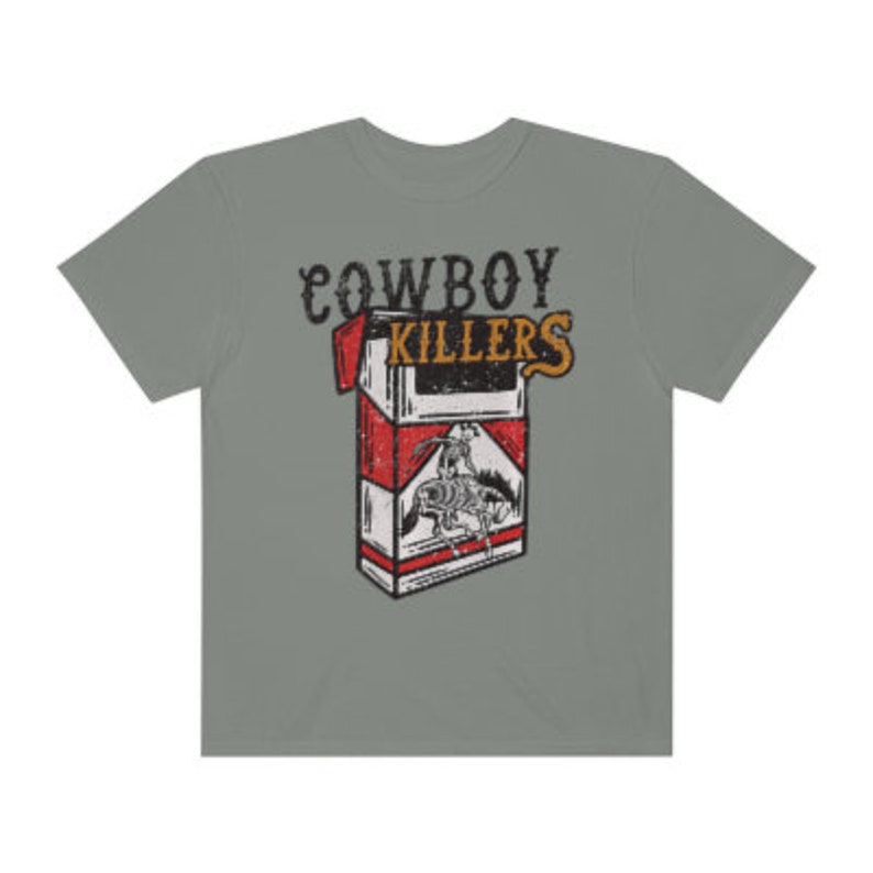 Peut inclure: Un t-shirt gris avec un imprim&eacute; vintage d'un paquet de cigarettes avec le texte "COWBOY KILLERS" imprim&eacute; dessus.