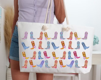 May include: A white canvas tote bag with a colorful pattern of cowboy boots. The boots are in various colors, including pink, blue, yellow, and green. The bag has a long, white strap.