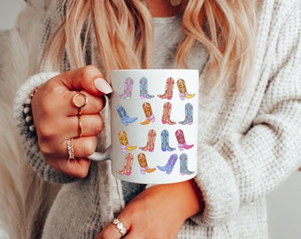 May include: White ceramic mug with a colorful pattern of cowboy boots. The boots are in various colors, including pink, blue, yellow, and orange.