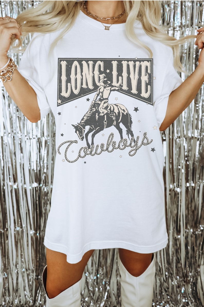 May include: White oversized t-shirt with a graphic print of a cowboy riding a bucking horse. The graphic has the text "Long Live Cowboys" in a vintage style.