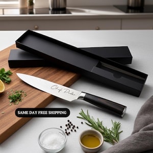 May include: A stainless steel chef's knife with a dark wooden handle and the inscription "Chef Pedro" on the blade. The knife is displayed with a black box, a wooden cutting board, and various cooking ingredients.