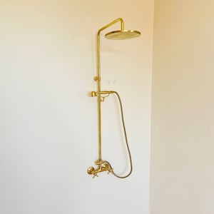Op de afbeelding: Een gouden douchekop en kraanset met een ronde douchekop en een handdouche.