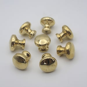 May include: Eight gold-toned cabinet knobs with a round, slightly raised design. The knobs have a smooth, polished finish.