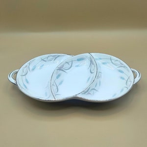 May include: A white ceramic serving dish with three sections. The dish has a blue and silver floral design with wheat stalks. The dish has two handles.