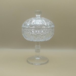 May include: A clear glass candy dish with a pedestal base and a domed lid. The dish has a cut glass design.
