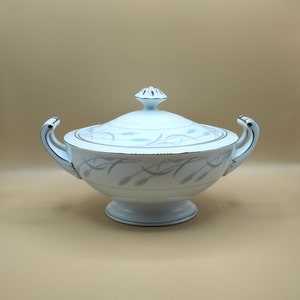 May include: White porcelain serving bowl with a lid. The bowl has a delicate design of wheat stalks in shades of blue and gray.