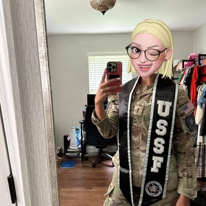 Peut inclure: Une personne porte un uniforme de camouflage avec une écharpe noire. L'écharpe porte le texte "USSF" en lettres blanches. L'uniforme a un écusson du drapeau américain sur la manche.