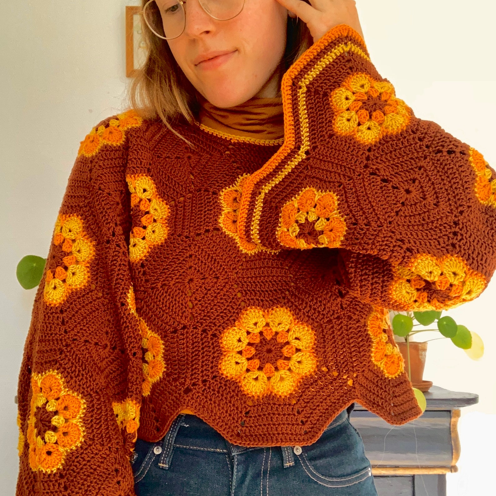 A red-orange and bright orange cropped sweater made from hexagons. In the middle of each red-orange hexagon is an orange flower.