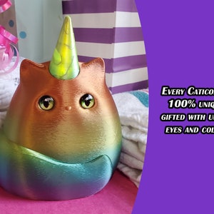 May include: A rainbow iridescent caticorn figurine with a yellow horn and large brown eyes. The text "EVERY Caticorn IS 100% UNIQUE, GIFTED WITH UNIQUE EYES AND COLORS" is visible in the background.