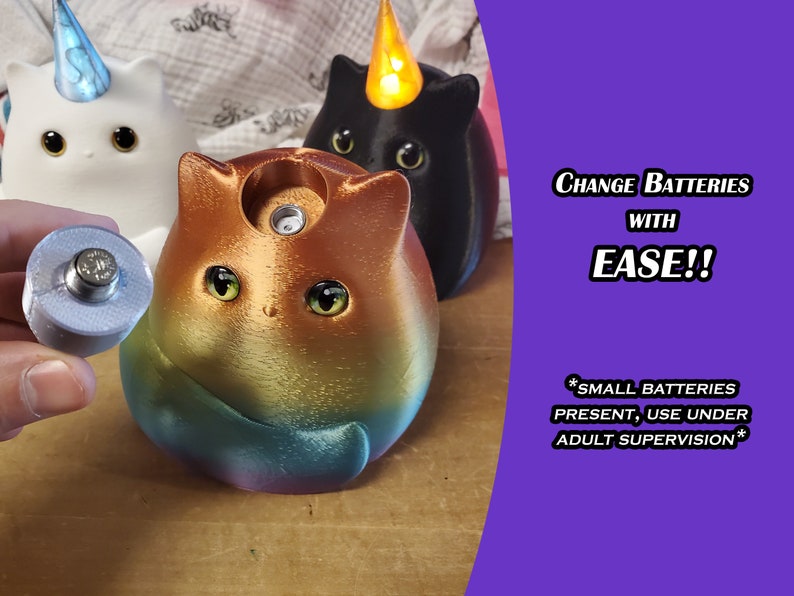May include: Three colorful cat-shaped night lights with a unicorn, black cat, and rainbow cat design. The rainbow cat is shown with a battery compartment open, revealing a small battery. The text on the image reads "Change Batteries with Ease!! *Small Batteries Present, Use Under Adult Supervision*"