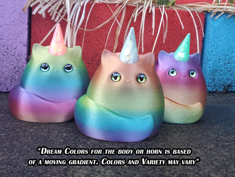 May include: Three small ceramic unicorn cat figurines with iridescent rainbow paint and a horn. The unicorn cats are sitting on a gray surface. *DREAM COLORS FOR THE BODY OR HORN IS BASED OF A MOVING GRADIENT. COLORS AND VARIETY MAY VARY*