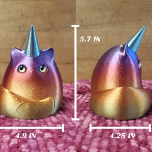 May include: A colorful, iridescent, 3D printed cat figurine with a unicorn horn. The cat is sitting on its haunches with its tail curled around its body. The figurine is approximately 5.7 inches tall, 4.9 inches wide, and 4.25 inches deep.
