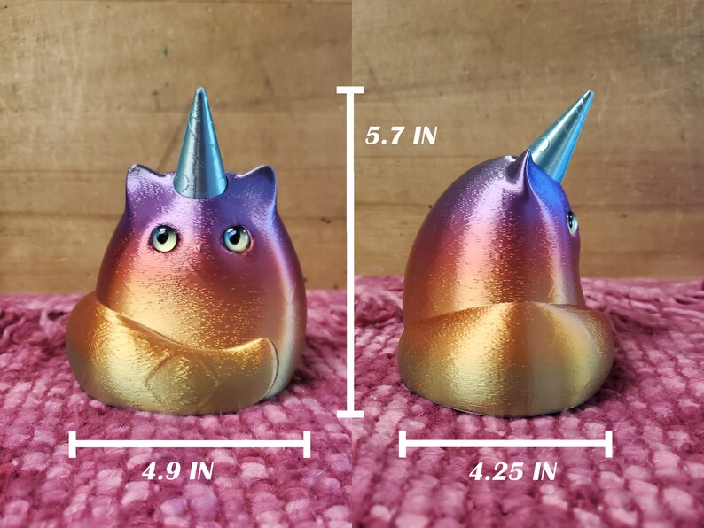 May include: A colorful, iridescent, 3D printed cat figurine with a unicorn horn. The cat is sitting on its haunches with its tail curled around its body. The figurine is approximately 5.7 inches tall, 4.9 inches wide, and 4.25 inches deep.