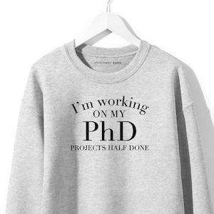 May include: A grey sweatshirt with the text "I'm working on my PhD Projects half done" printed on the front.