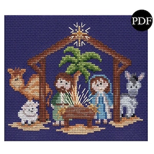 May include: A cross-stitch pattern featuring a nativity scene with a brown camel, a white sheep, a donkey, a manger, and a star. The scene is set against a dark blue background.