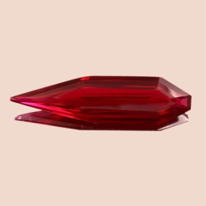 May include: A deep red, faceted gemstone with a pointed, elongated shape. The gemstone is cut into a unique, geometric design.