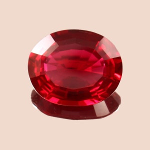 May include: A deep red oval-shaped gemstone with a faceted cut.