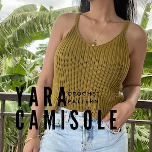 Pode incluir: Uma camisola sem mangas amarelo-mostarda com textura de crochê canelada vertical, alças finas e decote em V. O texto YARA CROCHET PATTERN CAMISOLE está sobreposto na imagem. A peça é combinada com calças de ganga azul-claras.