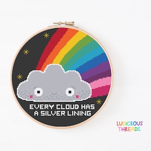 Puede incluir: Un aro de bordado de punto de cruz con fondo negro, un arcoíris, una nube gris con una cara sonriente y el texto "EVERY CLOUD HAS A SILVER LINING".