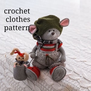 May include: A gray crocheted mouse wearing a green hat, red and white striped overalls, and a plaid scarf. The mouse is holding a small gray crocheted basket with a brown crocheted bunny inside.