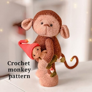 Puede incluir: Un mono de ganchillo marrón y beige sosteniendo una figura más pequeña con un gorro rojo. El mono tiene una cola rizada. El texto "Crochet monkey pattern" es visible.