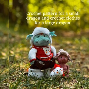 May include: Two crocheted dragon plushies, one large and one small. The larger dragon is wearing a red and white sweater, brown pants, and a white hat. The smaller dragon is wearing a brown sweater and hat. The text "Crochet pattern for a small dragon and crochet clothes for a large dragon." is displayed above the plushies.