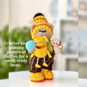 May include: A crocheted teddy bear wearing a yellow and orange striped hat, brown plaid overalls, and yellow shoes. A smaller yellow creature holds a blue ball, and a tiny white bear is in the pocket. The text reads: Crochet and knitting pattern of clothes for a small teddy bear.