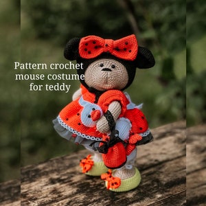 May include: Crochet pattern for a mouse costume for a teddy bear. The costume is red with black polka dots and a white bow. The teddy bear is holding a white crocheted mouse.