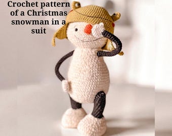 Könnte beinhalten: Ein gehäkelter Schneemann im Anzug, der einen beigefarbenen Hut mit Ohrenklappen trägt. Der Schneemann hat eine rote Nase, schwarze Arme und schwarz-weiße Beine. Der Text "Crochet pattern of a Christmas snowman in a suit" befindet sich im Bild.