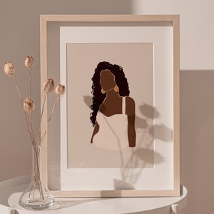 May include: A framed illustration of a woman with long, dark curly hair wearing a white tank top and gold earrings. The background is a light beige color.