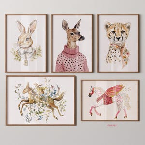 May include: Five framed watercolor illustrations of animals. The first shows a brown rabbit wearing a bow tie and a key around its neck. The second shows a deer wearing a pink polka dot sweater. The third shows a cheetah wearing a floral scarf. The fourth shows a deer with a rabbit riding on its back, surrounded by flowers. The fifth shows a white horse with pink and gold wings.