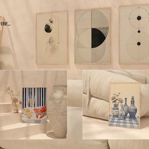 May include: A collection of framed art prints featuring abstract geometric designs and a still life of blue and white porcelain vases with flowers on a blue and white gingham tablecloth. The prints are displayed on a light beige wall with a sofa and a wooden stool in the foreground.