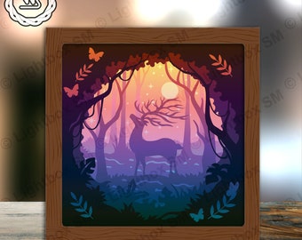 Puede incluir: Una obra de arte de papel recortado en 3D que representa un ciervo de pie en un bosque con una luna llena en el fondo. El ciervo es de color morado claro y el bosque es de color verde oscuro y azul. La luna es de color amarillo claro. La obra de arte está enmarcada en un marco de madera marrón.