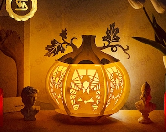 May include: A white pumpkin-shaped lamp with a spiderweb design and a silhouette of a person inside. The lamp is lit and casting a warm glow.