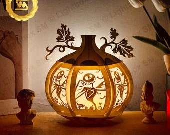 May include: A wooden pumpkin-shaped lamp with a silhouette of Jack Skellington from The Nightmare Before Christmas. The lamp is lit and casting a warm glow.