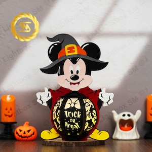 May include: A wooden Halloween decoration featuring Mickey Mouse dressed as a witch holding a pumpkin-shaped lantern that reads "Trick or Treat".
