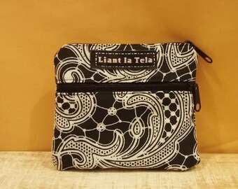 Può includere: Una piccola pochette con cerniera a motivo bianco e nero con il testo "Llant la Tela" sul davanti.