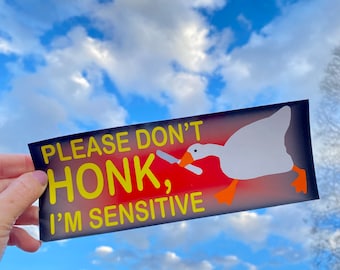 Op de afbeelding: Een zwarte en rode sticker met een witte gans die een mes vasthoudt. De sticker zegt "Toeteren aub niet, ik ben gevoelig".
