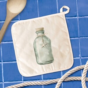 May include: A square, off-white pot holder with a loop for hanging. It features a watercolor illustration of a glass bottle with a cork, tied with twine and a starfish. The background is a blue tile.