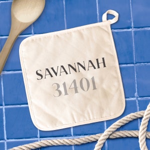 May include: A white cotton pot holder with the text "SAVANNAH 31401" printed in black and gray.
