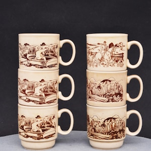 May include: Set of six brown and white ceramic mugs with a country scene design. Each mug features a different scene with a boat, a person rowing, and a landscape. The mugs are stacked in two piles of three.