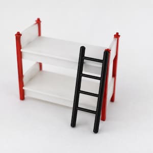 May include: A miniature bunk bed featuring a white frame with two horizontal platforms and four bright red vertical corner posts. A separate, detachable black ladder with four rungs is positioned leaning against the front of the white bed structure.