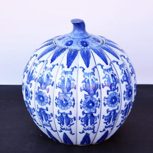 Puede incluir: Un jarrón de calabaza de porcelana azul y blanco con tapa. El jarrón está decorado con un patrón floral y tiene una textura acanalada.