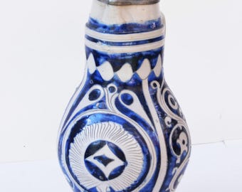 May include: A blue and white ceramic stein with a pewter lid and base. The stein has a floral design and a diamond shape in the center.