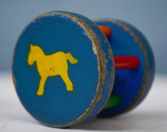 Op de afbeelding: Een vintage houten speelgoed met een blauw en geel geschilderd paard aan de ene kant en kleurrijke houten pinnen aan de andere kant.