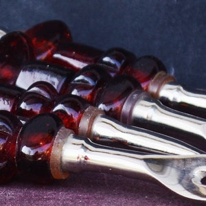 Peut inclure: Ensemble de quatre ustensiles de service en argent avec des manches en verre rouge. Les ustensiles comprennent une fourchette, une cuillère et deux petites fourchettes.